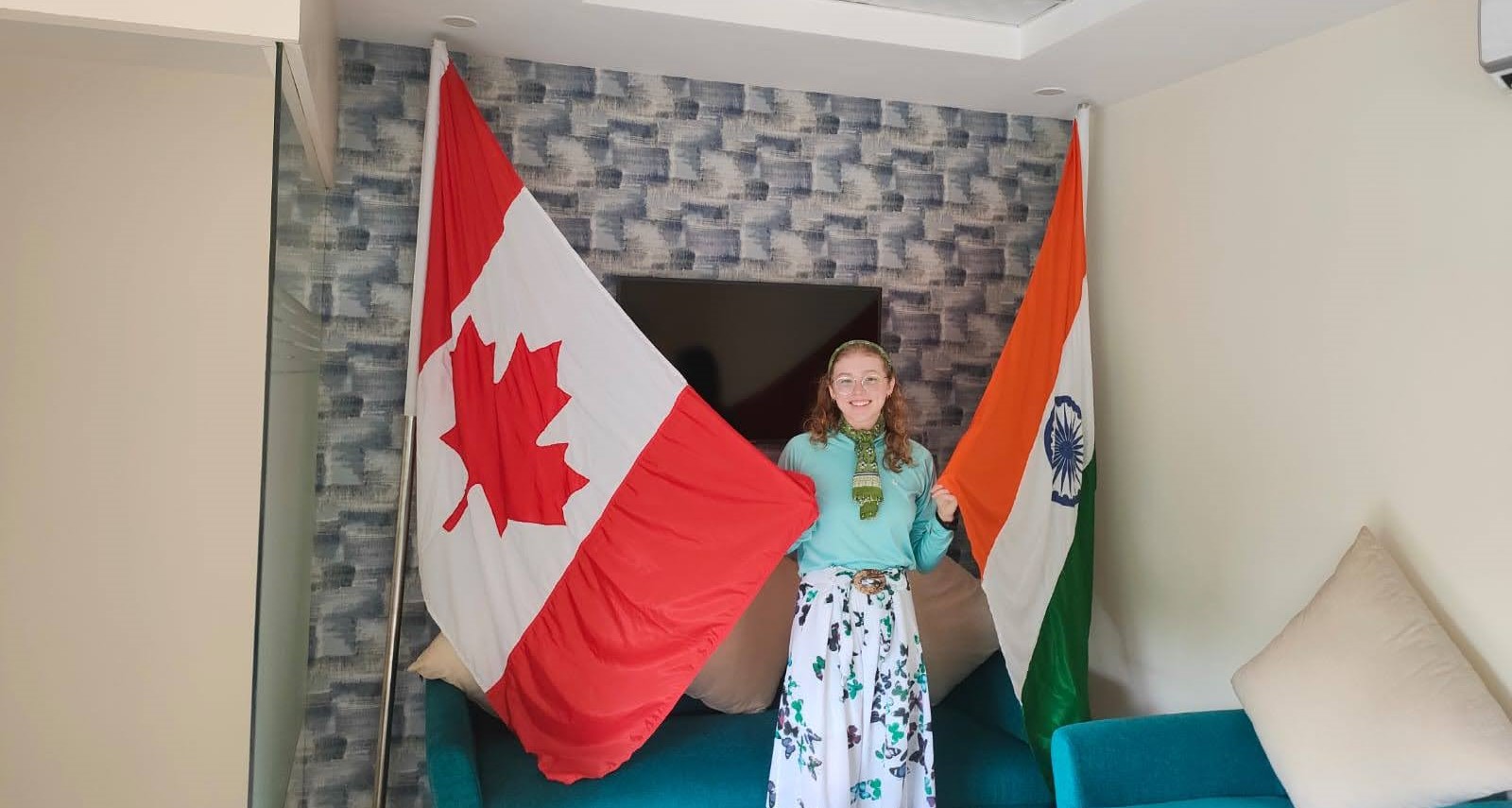 Julia standing between the Canadian flag and the Indian flag at the Shastri Indo-Canadian Institute in Delhi.